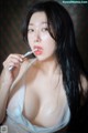 A woman with long black hair holding a toothbrush in her mouth.