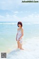 A woman standing in the ocean wearing a white dress.