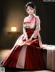 A woman in a red and white kimono sitting on a table.