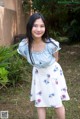 A woman in a blue top and a white skirt posing for a picture.