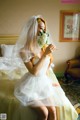 A woman in a wedding dress sitting on a bed.