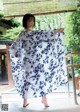 A woman in a blue and white kimono standing in front of a window.