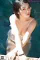 A woman in a white dress sitting in a pool.