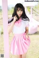 A woman in a pink and white uniform posing for a picture.