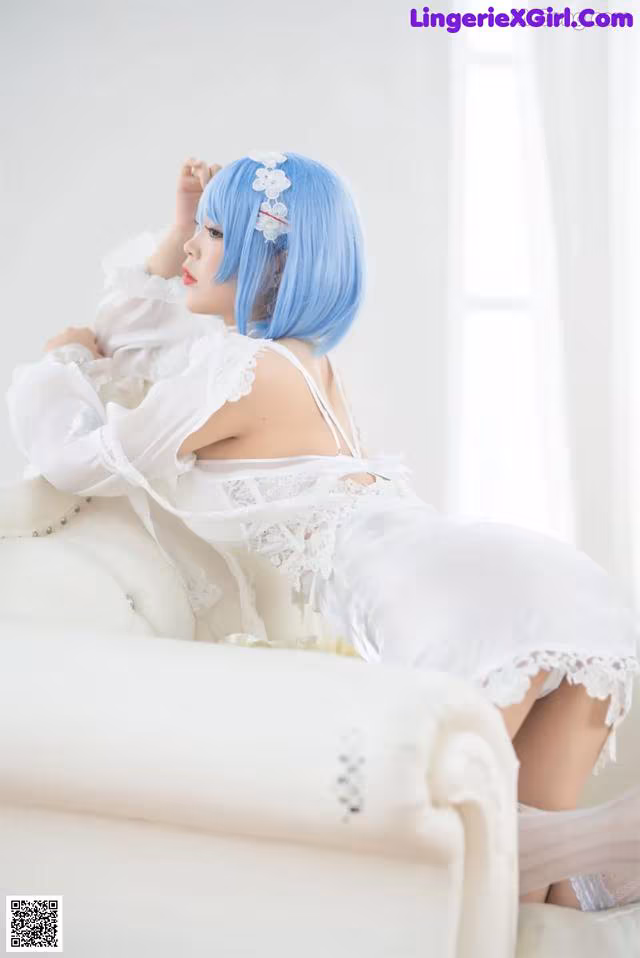 A woman in a white dress sitting on a white couch.