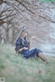 A woman in a blue dress sitting in the grass.