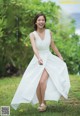 A woman in a white dress is standing in the grass.