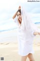 A woman in a white shirt is standing on the beach.