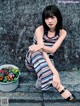 A woman sitting on the ground next to a potted plant.