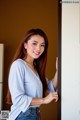 A woman leaning against a wall with her hand on the door.